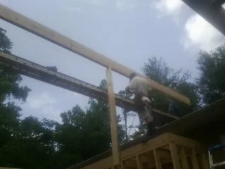 Carpenter setting a ridge beam over a new addition frame — Ice Dam Removal by Roofing Brothers in Fairland