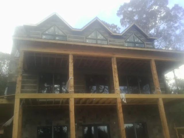 Dormers and porch framing on a large log home under construction — Roof Coating work by our crew in Fairland