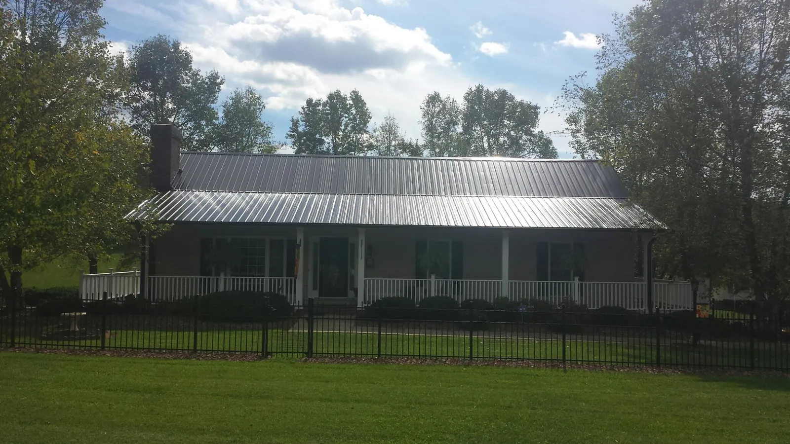 Gray metal roof on a brick ranch with a full width front porch — Gutter Guard Installation work by our crew in Fairland