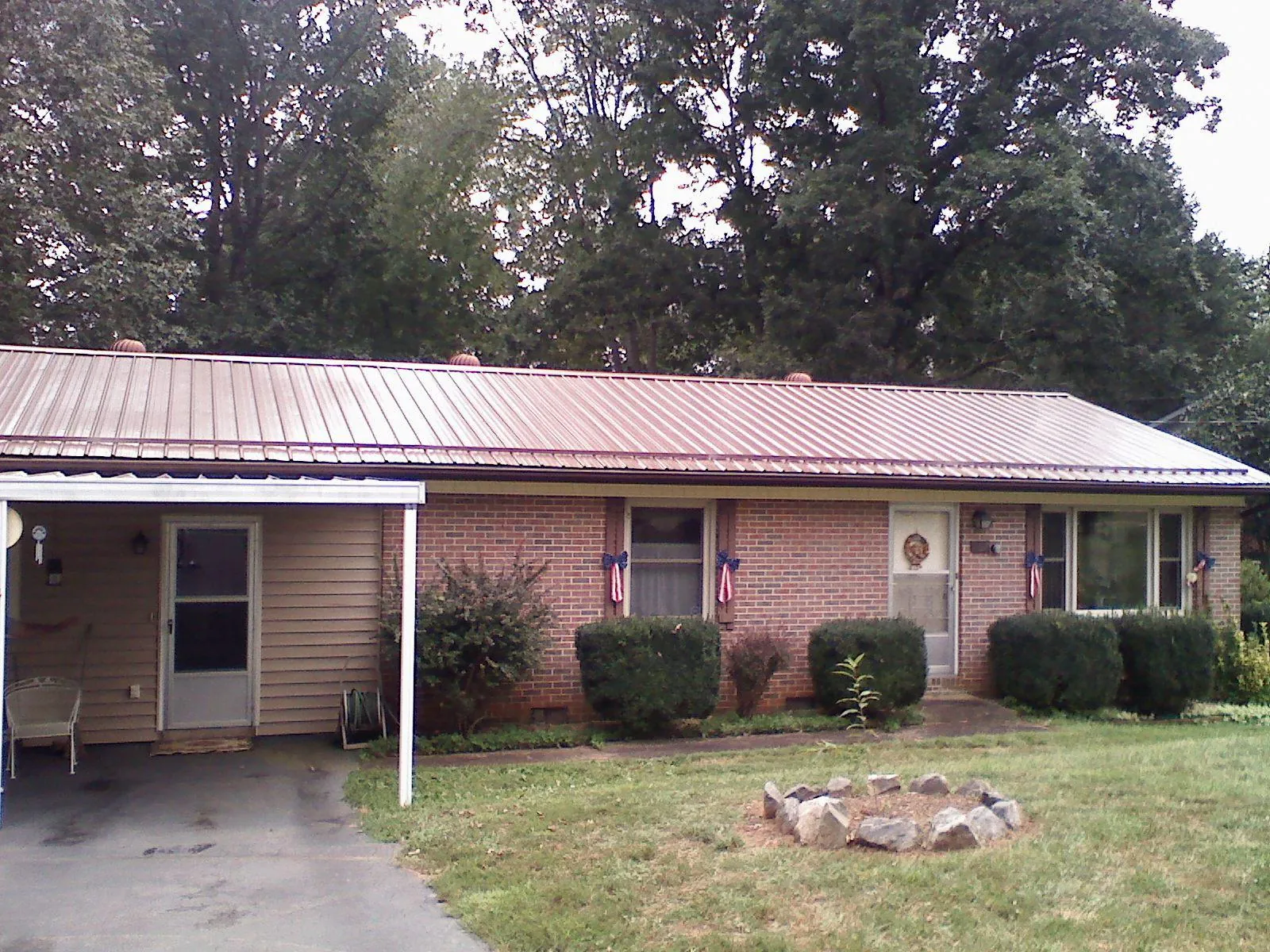 Bronze metal roof and carport on a brick ranch home — Roof Repair work by our crew in Fairland