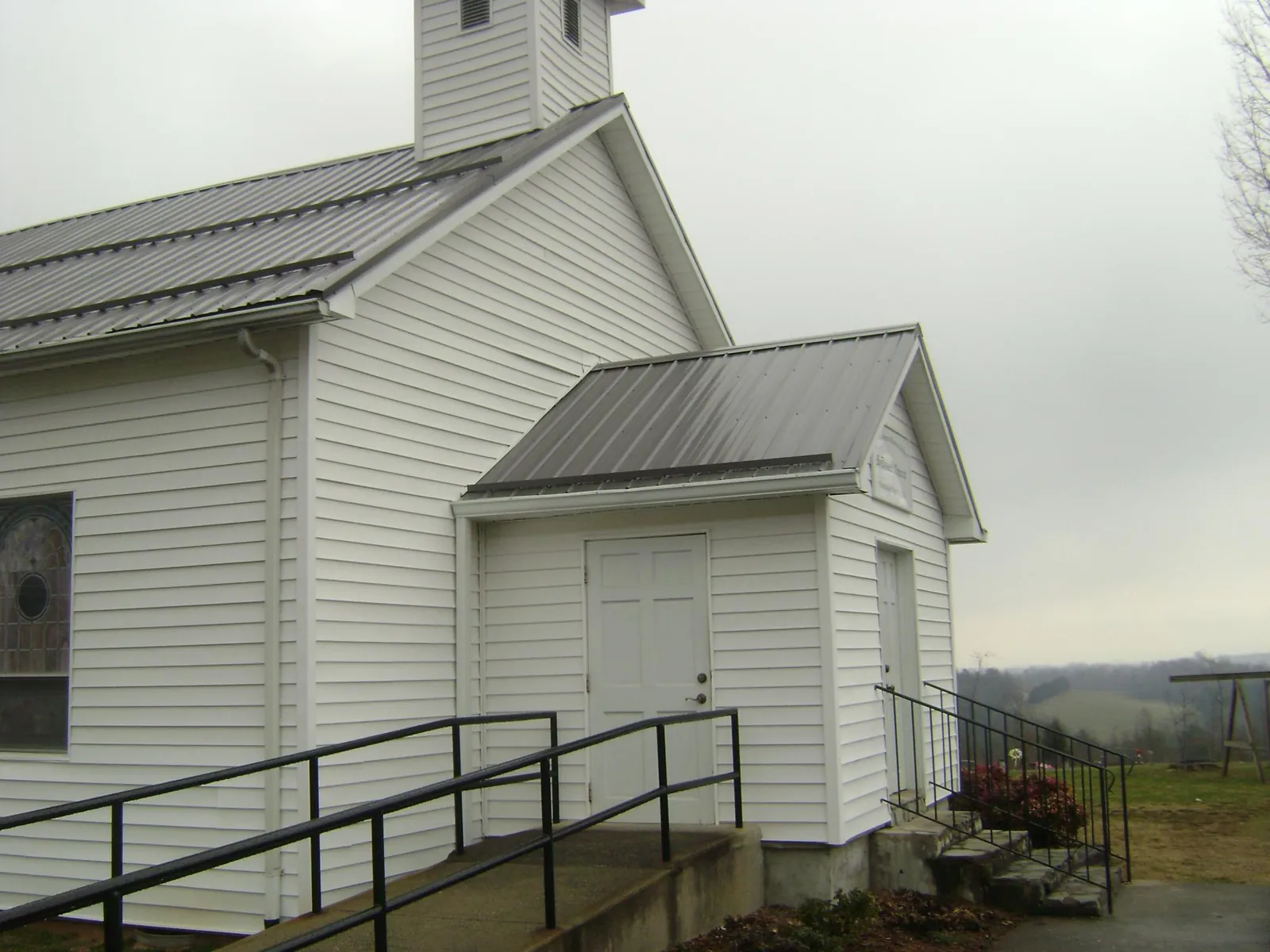 Gray metal roof on a white clapboard church with a steeple in Fairland