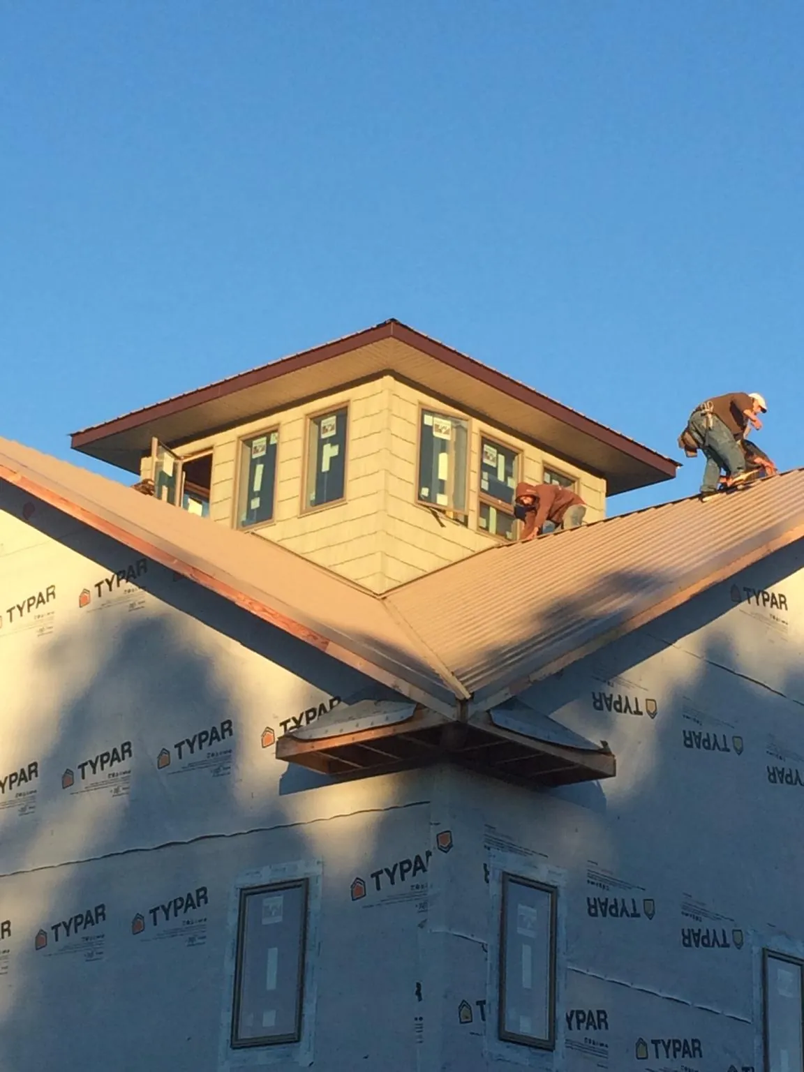 Roofers working around a rooftop cupola on a new metal roof at sunset — Roof Waterproofing in Fairland by Roofing Brothers